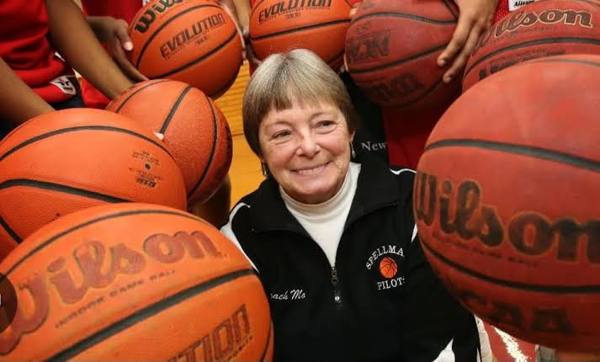 Coach Jane Morris of Spellman surrounded by basketballs held by her players